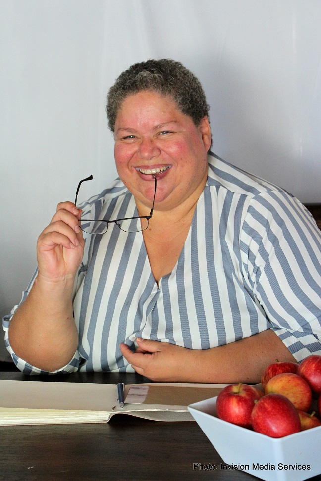 Simone Eiman at desk with notebook and apple, ready to guide